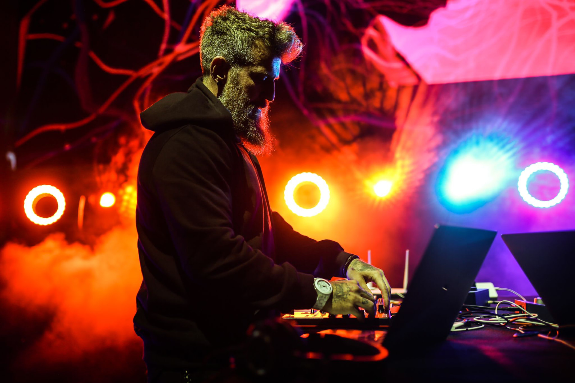 SW3NTON performing under neon red and blue stage lights with haze