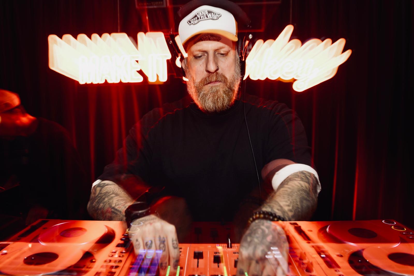 SW3NTON mixing on CDJs in front of a neon sign