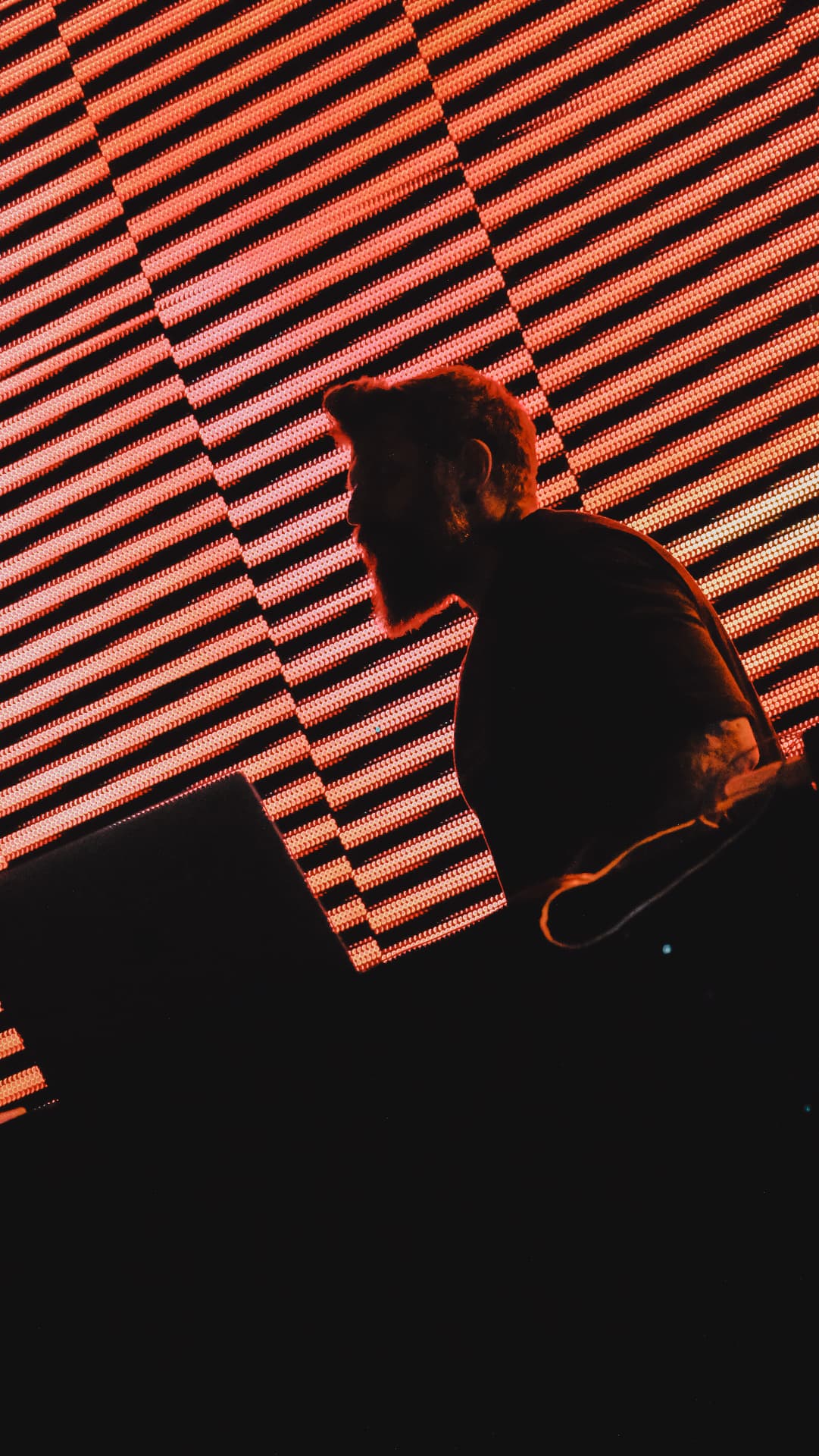 SW3NTON silhouetted against a red LED wall